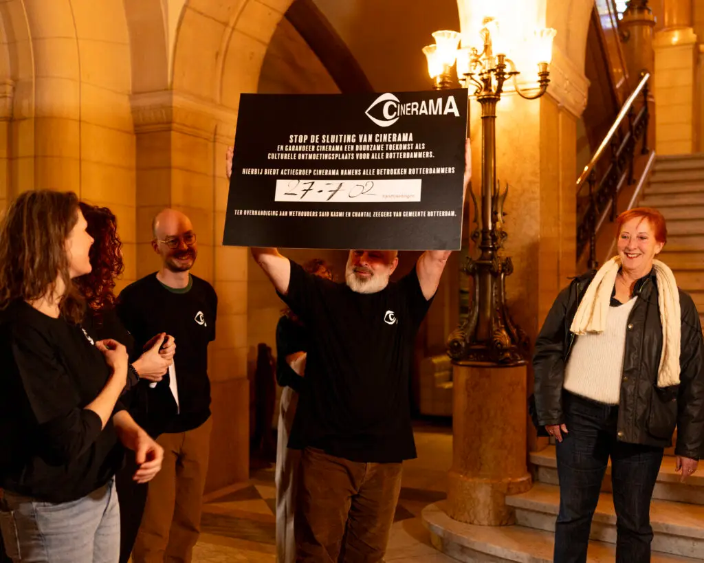 Man presenteert triomfantelijk de 27702 keer geketende petitie tegen de sluiting van Cinerama.